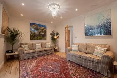 a living room with two couches and a rug at Chy An Gweal Farm Cottage in Carbis Bay