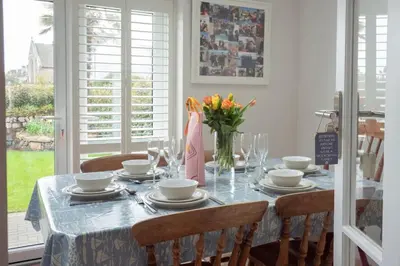 a dining room table with a vase of flowers on it at Chy An Gweal Farm Cottage in Carbis Bay