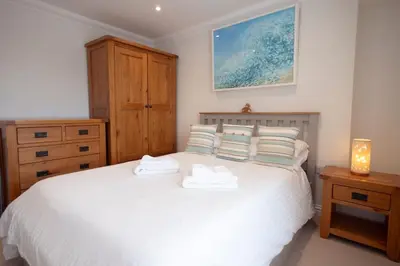a bedroom with a white bed with two towels on it at Chy An Gweal Farm Cottage in Carbis Bay