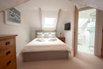 a bedroom with a bed with white sheets and a window at Chy An Gweal Farm Cottage in Carbis Bay