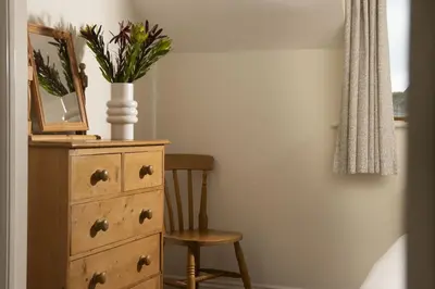 a dresser with a vase of flowers on top of it at Godolphin in Wadebridge