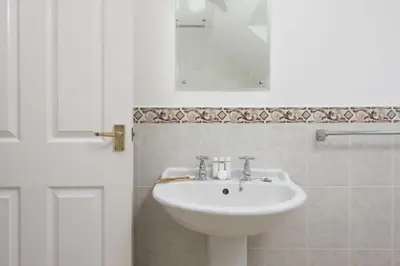 a white bathroom with a sink and a mirror at Godolphin in Wadebridge