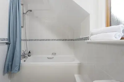 a white bathroom with a tub and a sink at Godolphin in Wadebridge