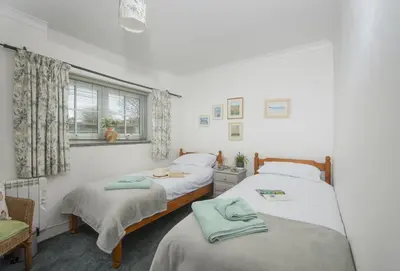 two twin beds in a room with a window at Roseland Cottage in Truro