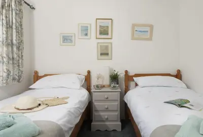 two beds in a bedroom with a hat on a night stand at Roseland Cottage in Truro