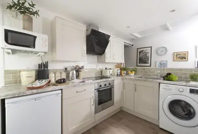 a kitchen with white cabinets and a washer and dryer at Roseland Cottage in Truro