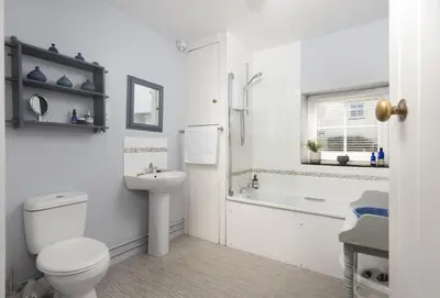 a white bathroom with a toilet and a sink at Roseland Cottage in Truro