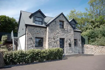 a stone house with a gate and a fence at Chy An Gweal Farm Coach House in Carbis Bay