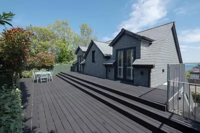 a wooden deck in front of a house at Chy An Gweal Farm Coach House in Carbis Bay