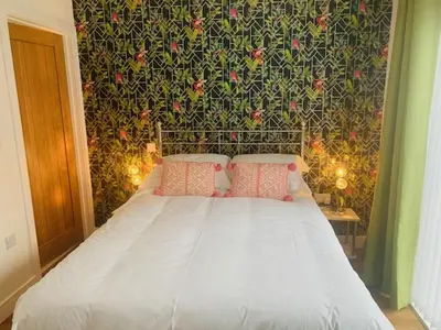a bedroom with a white bed with a floral wall at double room in Wadebridge