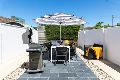 a patio with an umbrella and a table and chairs at Beachwalk in Newquay