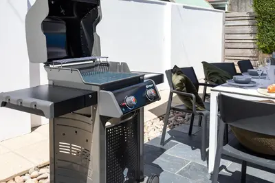 a grill on a patio with a table and chairs at Beachwalk in Newquay