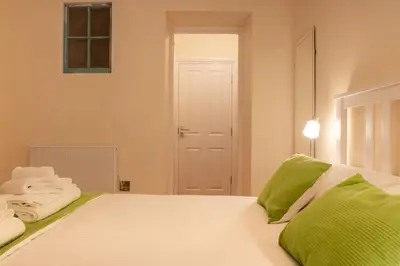 a white bed with green and white towels on it at Chandler's Lodge B&B in Camelford