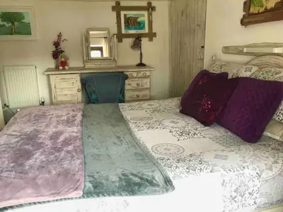 a bedroom with a bed with a dresser and a mirror at Malvern Cottage in Perranporth