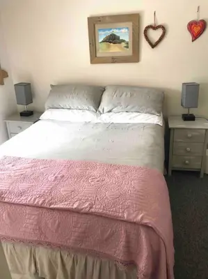 a bedroom with a bed and two tables with lamps at Malvern Cottage in Perranporth