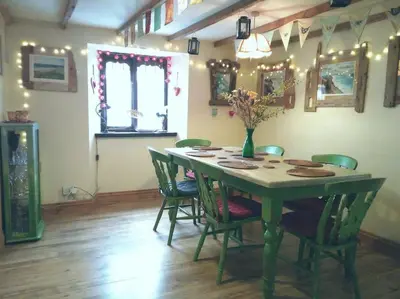 a dining room table with chairs and a vase with flowers at Malvern Cottage in Perranporth
