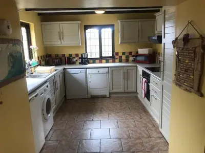a kitchen with white cabinets and a tile floor at Malvern Cottage in Perranporth