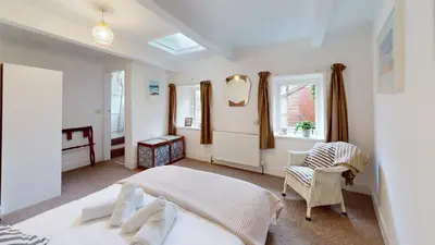 a bedroom with a bed and a chair and windows at St Ives The Villa in St Ives
