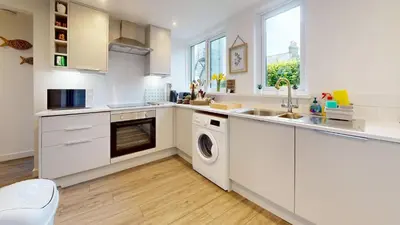 a kitchen with white cabinets and a washer and dryer at St Ives The Villa in St Ives