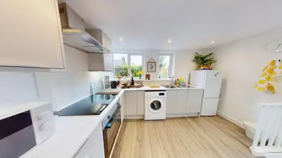 a kitchen with white cabinets and a washer and dryer at St Ives The Villa in St Ives