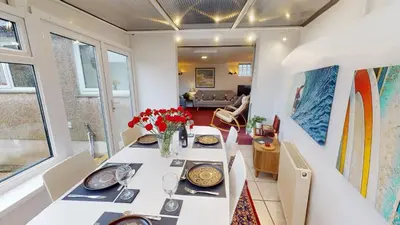 a dining room with a white table with flowers on it at St Ives The Villa in St Ives
