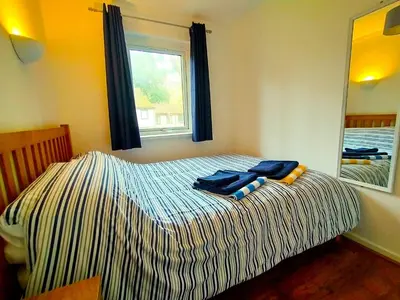 a bed in a bedroom with a mirror on it at Painters Cottage 2-Bed Chalet nr St Ives & Hayle in St Ives