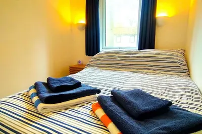 a bedroom with two beds with towels on them at Painters Cottage 2-Bed Chalet nr St Ives & Hayle in St Ives