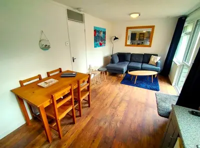 a living room with a table and a blue couch at Painters Cottage 2-Bed Chalet nr St Ives & Hayle in St Ives