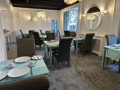 a dining room with tables and chairs and a mirror at Tintagel Arms Bed and Breakfast in Tintagel