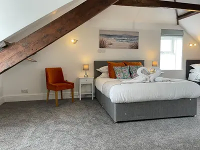 a bedroom with two beds and a orange chair at Tintagel Arms Bed and Breakfast in Tintagel