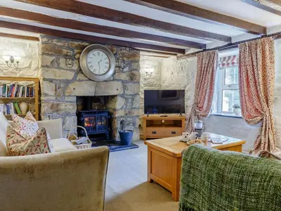 a living room with a stone fireplace and a clock on the wall at 3 Bed in Newquay oc-82369 in Mitchell