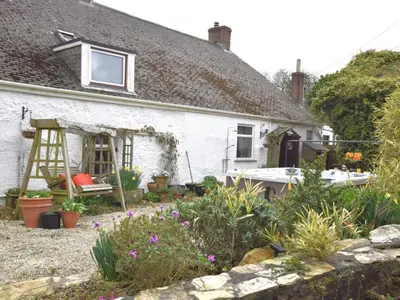 a white cottage with a garden in front of it at 3 Bed in Newquay oc-82369 in Mitchell