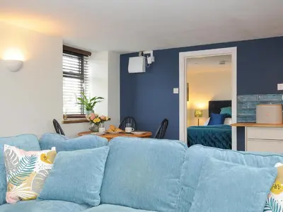 a living room with blue walls and a blue couch at The Bower in Helston