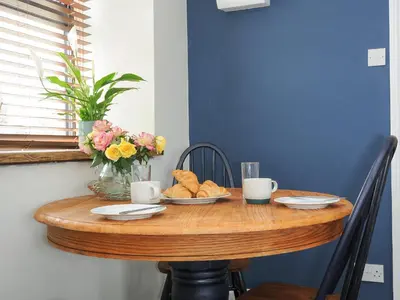 a wooden table with a bowl of bread and flowers on it at The Bower in Helston