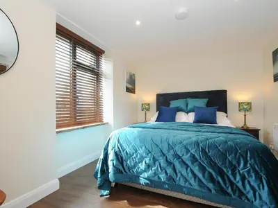 a bedroom with a bed with blue sheets and a window at The Bower in Helston