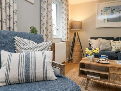 a living room with a blue couch and a table at Breeze Cottage in Falmouth