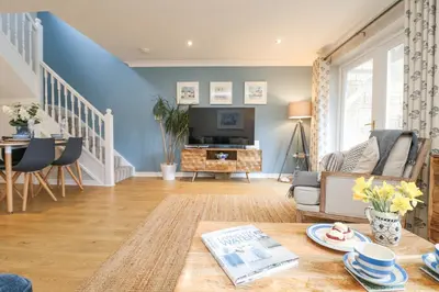 a living room with a table and a tv at Breeze Cottage in Falmouth