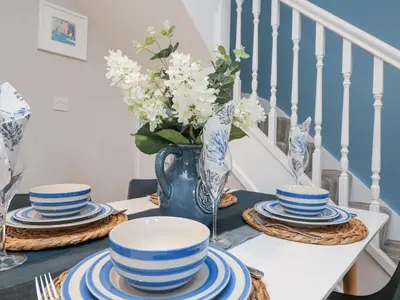 a table with blue and white dishes and a vase with flowers at Breeze Cottage in Falmouth