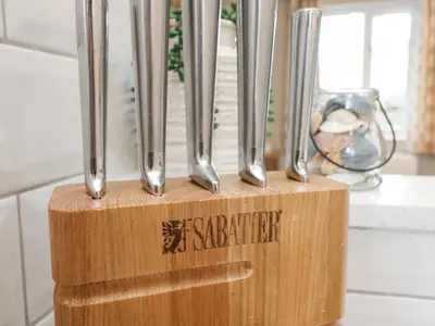 a wooden block with silver utensils on a counter at Breeze Cottage in Falmouth