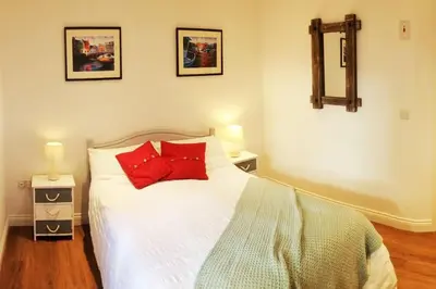 a bedroom with a white bed with two red pillows at Sunny Corner - Coastal apartment near the beach in Crantock