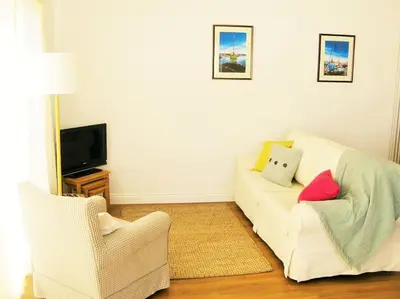 a living room with a white couch and a television at Sunny Corner - Coastal apartment near the beach in Crantock