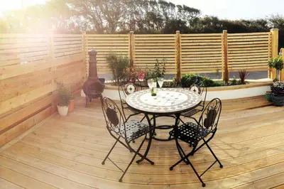 a patio with a table and chairs on a wooden deck at Sunny Corner - Coastal apartment near the beach in Crantock