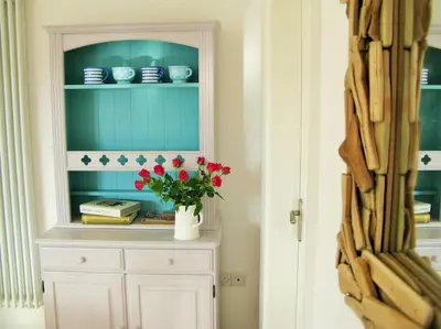 a cabinet with a vase with red flowers in it at Sunny Corner - Coastal apartment near the beach in Crantock