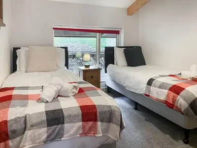 a bedroom with two beds and a window at Trebellan in Porthtowan