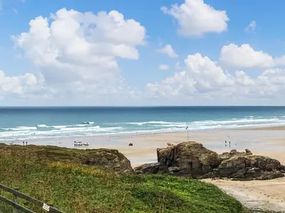 a beach with people on the sand and the ocean at Trebellan in Porthtowan