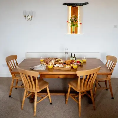 a wooden table with chairs and food on it at Treworgie Barton - Duchy in Bude