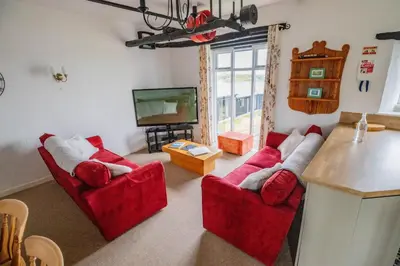 a living room with two red couches and a television at Treworgie Barton - Duchy in Bude