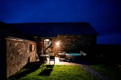 a stone house with a tub in the yard at night at Treworgie Barton - Duchy in Bude
