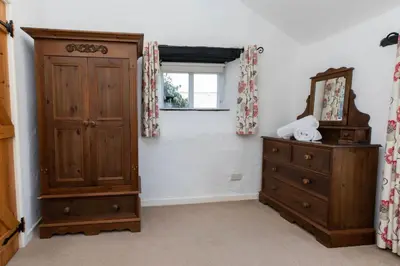 a room with a wooden cabinet and a mirror and a dresser at Treworgie Barton - Butterwell in Bude