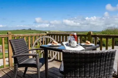 a table with two chairs and food on a deck at Treworgie Barton - Butterwell in Bude